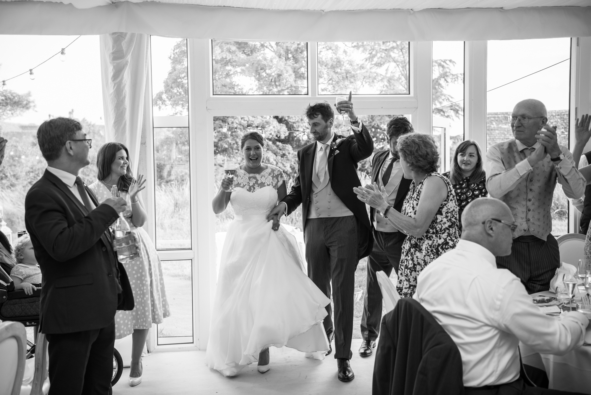 A bride and groom entering the wedding marquee at Whatley Manor